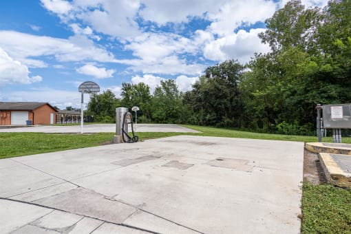 a basketball court in a park with a basketball hoop and a bench
