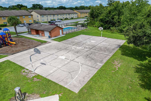 an aerial view of a basketball court in a backyard with a playground and a pool