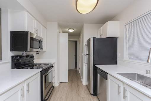 A kitchen with black appliances and white cabinets.