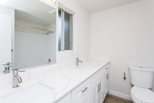 A white bathroom with a toilet, sink, and mirror.