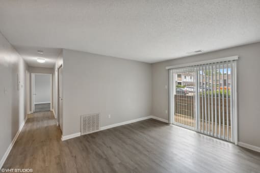 a spacious living room with a sliding glass door to a balcony