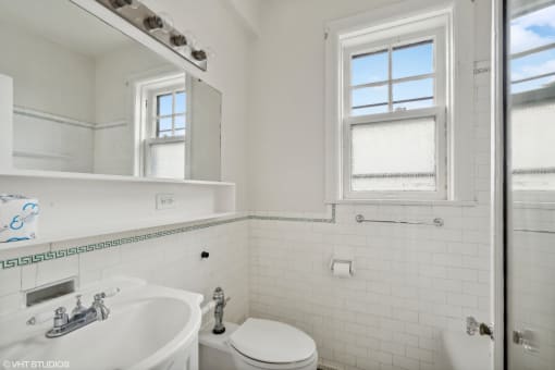 a white bathroom with a sink toilet and a window  at The Embassy in St Louis