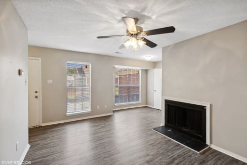 an empty living room with a fireplace and a ceiling fan at The Birches Apartment Homes, Memphis