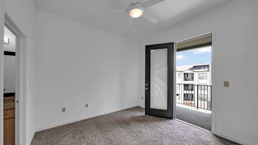A room with a ceiling fan and a door leading to a balcony.