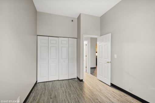 the living room of an empty apartment with white doors and wood flooring at Delmar Loop Apartments, Missouri, 63112