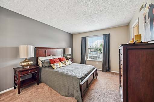 A bedroom with a large bed and a window overlooking a balcony.