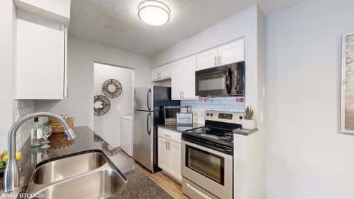 a kitchen with stainless steel appliances and white cabinets at Island Club Apartments, Columbus