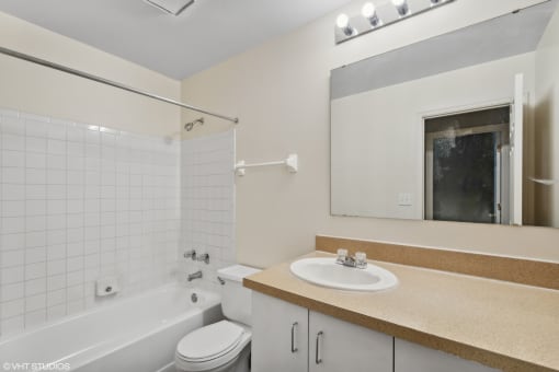 a bathroom with a sink toilet and tub and a mirror at Delmar Loop Apartments, St. Louis
