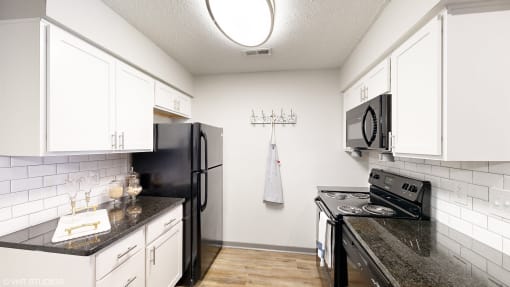 a kitchen with black appliances and white cabinets at Silvertree at Little Turtle Apartments, Westerville