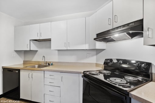 a kitchen with white cabinets and black appliances and a sink at Delmar Loop Apartments, Missouri