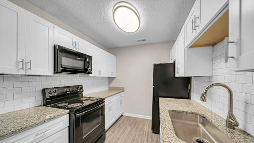 A kitchen with black appliances and white cabinets. at The Stella Apartments, Memphis, 38134