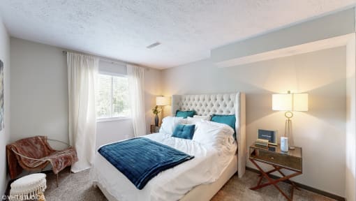 a bedroom with a bed and a chair and a window at Runaway Bay Apartments, Columbus, Ohio