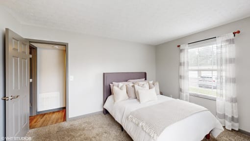 a bedroom with a bed and a door to a bathroom at Island Club Apartments, Columbus, OH
