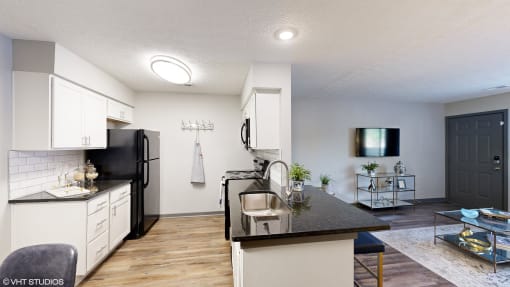 a kitchen and living room with white cabinets and black counter tops at Silvertree at Little Turtle Apartments, Westerville, 43081