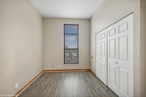 an empty room with wood flooring and white walls and doors and a window at Delmar Loop Apartments, Missouri, 63112