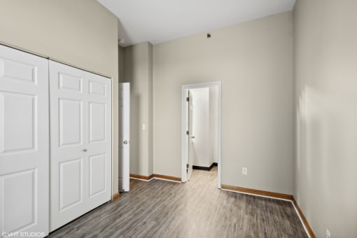 an empty bedroom with white doors and wood flooring at Delmar Loop Apartments, Missouri, 63112