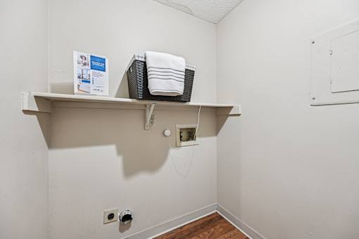 A white shelf with a basket and towels on it.