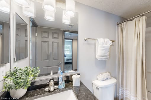 a bathroom with a large mirror and a toilet and a sink at Island Club Apartments, Ohio