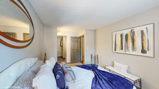 a bedroom with a large bed and a mirror on the wall at Silvertree at Little Turtle Apartments, Westerville, Ohio