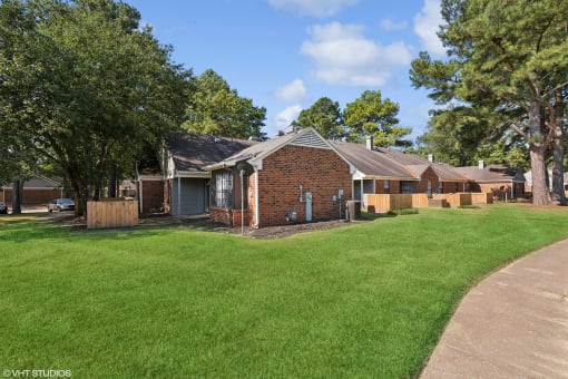 a small brick house with a yard and trees at The Birches Apartment Homes, Memphis, TN