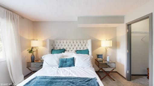 a bedroom with a white bed and blue pillows at Runaway Bay Apartments, Columbus, Ohio