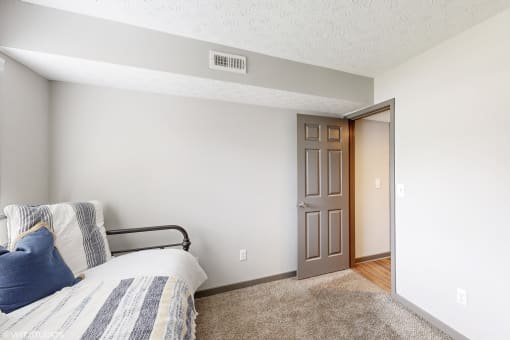 a bedroom with a bed and a door to a bathroom at Island Club Apartments, Columbus, OH, 43235