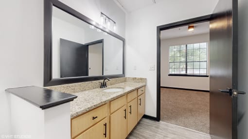 a bathroom with a sink and a mirror and a door to a room  at Bristol On Union Apartment Homes, Tennessee