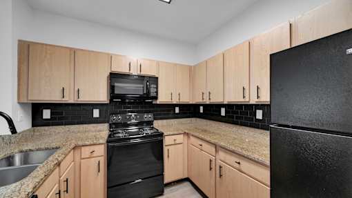 A kitchen with black appliances and wooden cabinets.
