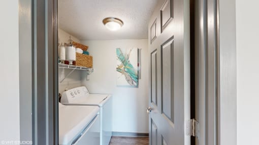 a laundry room with a washer and dryer and a blue door at Runaway Bay Apartments, Columbus, 43204