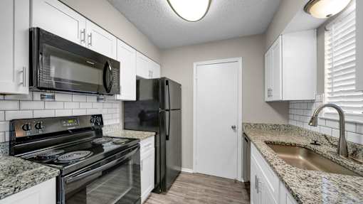 A kitchen with black appliances and white cabinets.