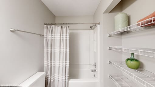 a spacious bathroom with a shower and a shower curtain and shelves at Karric Place of Dublin Apartments, Ohio