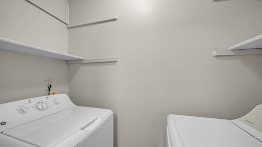 Two white washing machines in a small laundry room.