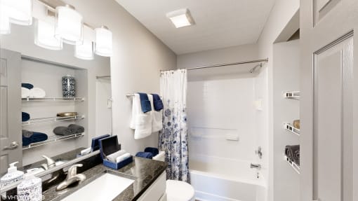 a bathroom with a shower and a sink and a mirror at Silvertree at Little Turtle Apartments, Westerville, OH, 43081