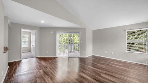 A spacious room with wooden floors and a large window.