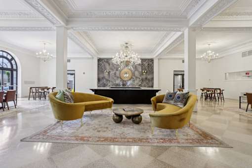 A large room with a yellow couch and a chandelier.