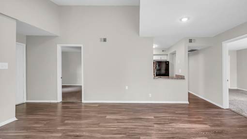 A spacious living room with wood flooring and white walls.