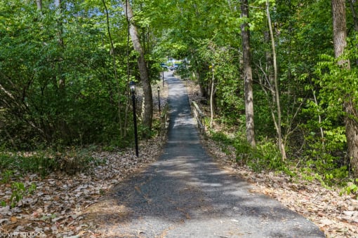 a dirt road with trees on both sides and a fence on the side at Silvertree at Little Turtle Apartments, Westerville, OH