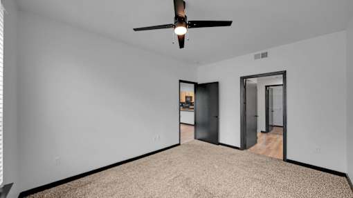 A room with a ceiling fan and carpeted floor.