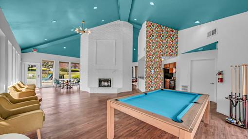 A pool table is in the middle of a room with a fireplace and a chair.