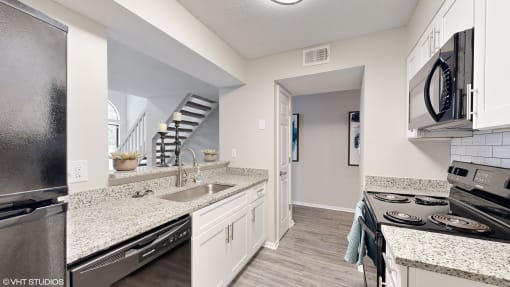 a kitchen with granite counter tops and stainless steel appliances at The Vale Apartments and Townhomes, Tennessee