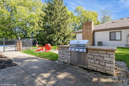 A backyard with a stone wall and a grill at Karric Place of Dublin Apartments, Dublin, 43016