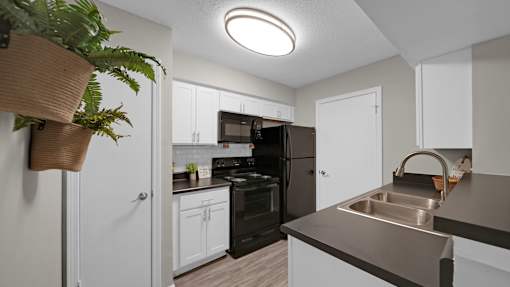 A kitchen with a black refrigerator and white cabinets. at The Local Apartments, Memphis, TN