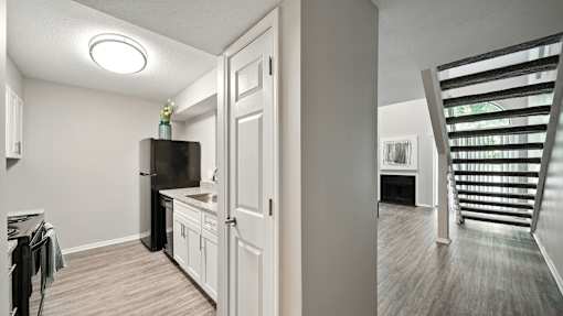 A kitchen with white cabinets and a black fridge is shown.