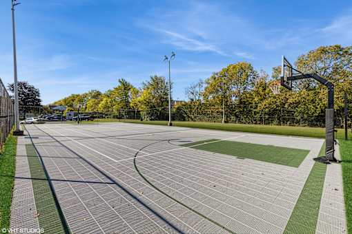A basketball court with a green and grey surface and a basketball hoop on the right side. at Island Club Apartments, Columbus