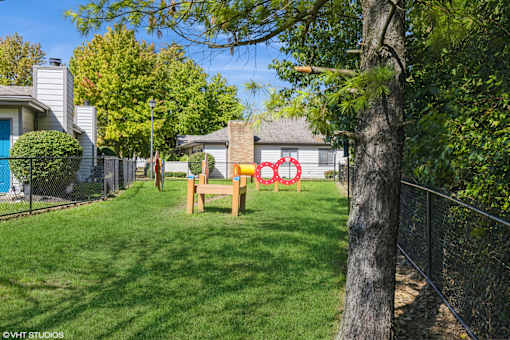 A backyard with a wooden bench and a tree. at Karric Place of Dublin Apartments, Dublin, OH, 43016