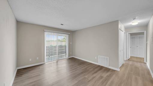 A spacious room with wooden flooring and a sliding glass door leading to a balcony. at The Stella Apartments, Tennessee, 38134