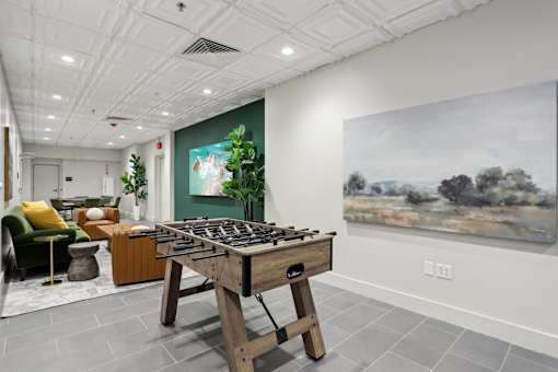 A room with a green chair, a wooden table, and a painting on the wall.