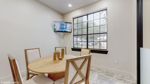 a dining room with a table and chairs and a tv on the wall at Bristol On Union Apartment Homes, Memphis
