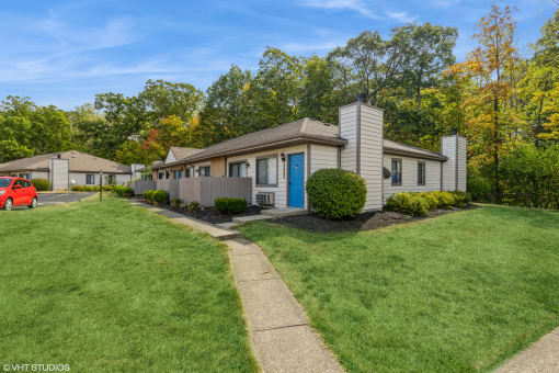 a white house with a blue door and a lawn and trees at Silvertree at Little Turtle Apartments, Westerville, OH, 43081