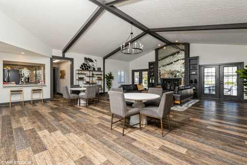 A modern dining room with a wooden floor and a large table surrounded by chairs at Karric Place of Dublin Apartments, Ohio, 43016